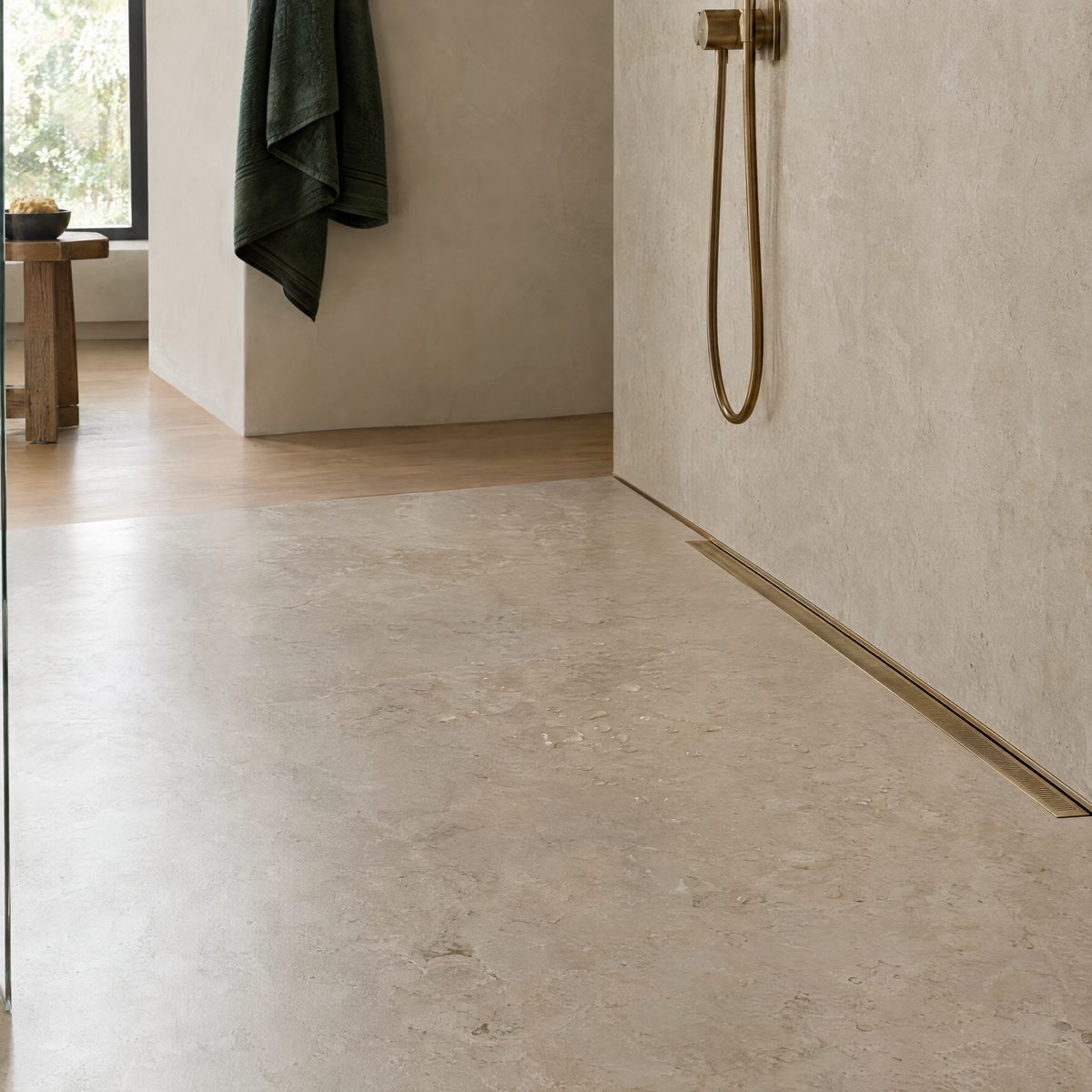Curbless shower floor in large-format stone-look porcelain sloping to a brass linear drain at the wall